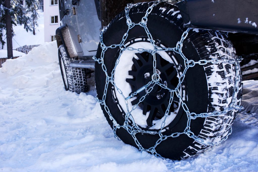 Opona samochodowa z zamontowanym łańcuchem śniegowym.
